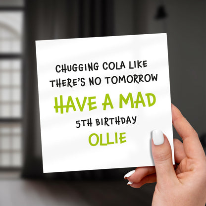 Hand holding a card with humorous birthday message on a blurred background