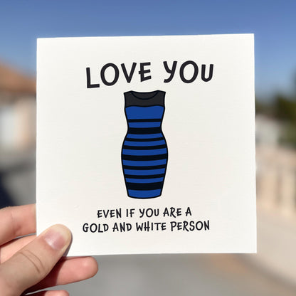 Card with a blue and black striped dress illustration and text held by a hand against a blurred outdoor background.