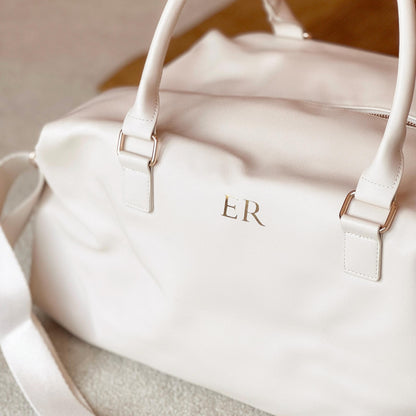 White handbag with gold initials 'ER' on a neutral background