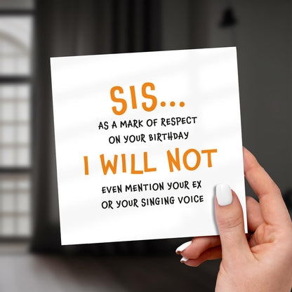 Hand holding a card with humorous birthday message for a sister.