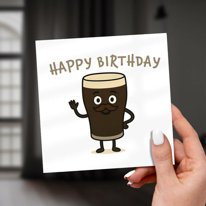 Hand holding a birthday card with a cartoon coffee cup character and 'Happy Birthday' text.
