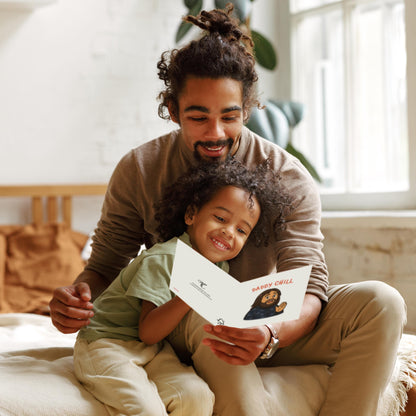 Man and child sitting together, looking at a card in a bright room.