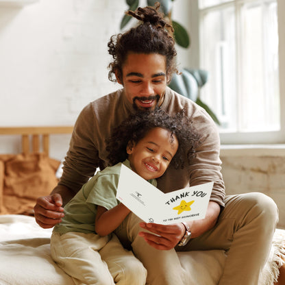 Man and child sitting together holding a 'Thank You' card in a cozy indoor setting.