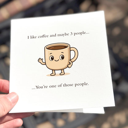 Card with cartoon coffee cup and text held by a hand