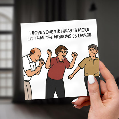 Cartoon birthday card with three men and humorous text, held by a hand.