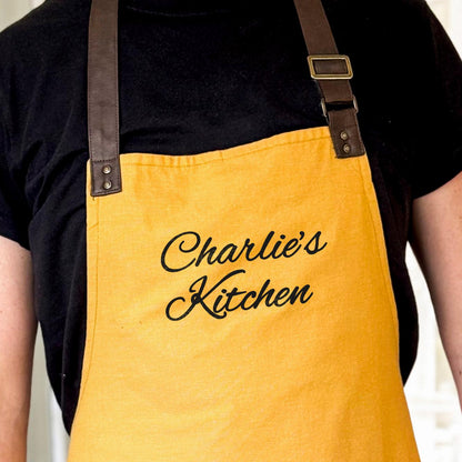 Yellow apron with 'Charlie's Kitchen' text worn by a person