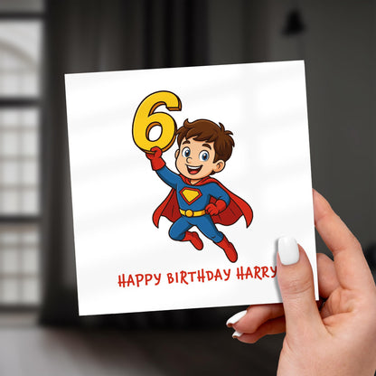 Birthday card with a superhero design holding the number 6, held by a hand.