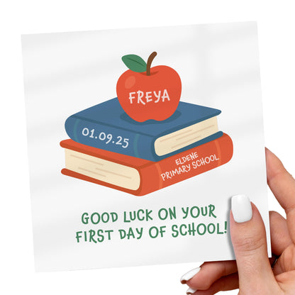 Card with books and an apple illustration for a first day of school celebration, held by a hand.