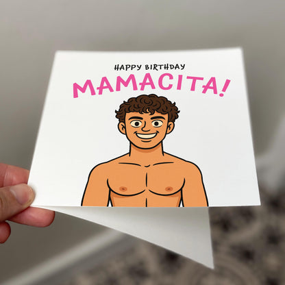 A square birthday card featuring a cartoon-style shirtless guy smiling with the caption “Happy Birthday Mamacita!” in bold pink and black lettering. The design references a viral Love Island moment and is printed on off-white textured card, shown against a neutral tiled background.