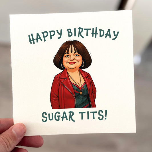 A square greeting card held by hand, featuring a cartoon-style illustration of a woman in a red jacket with the caption “Happy Birthday Sugar Tits!” in bold green text. The design is printed on off-white textured card, styled in a clean, lifestyle photo.