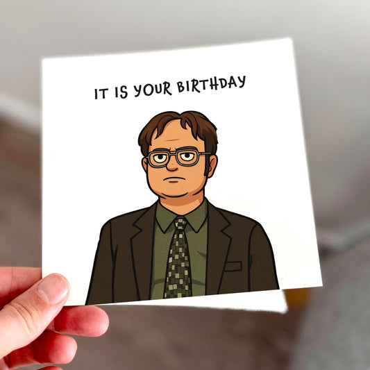Card with cartoon character and 'It is your birthday' text held by a hand.