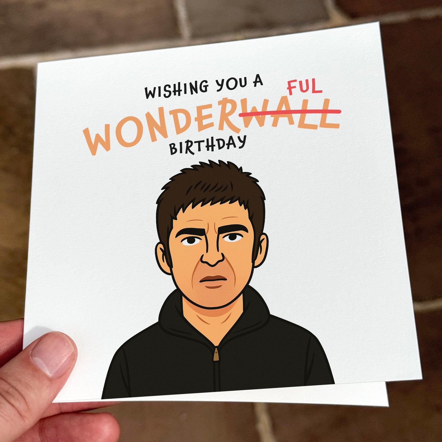 Card with a cartoon illustration of a person and text 'Wishing you a FUL WONDERWALL birthday' held by a hand.