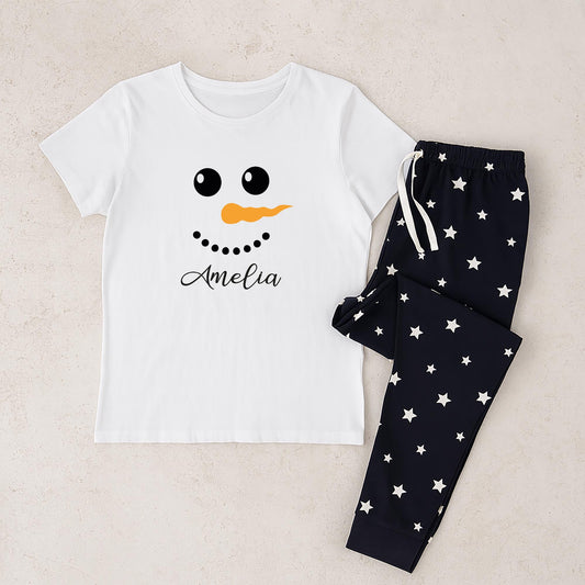 White t-shirt with snowman face design and black pants with star pattern on a beige background